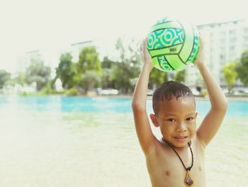 Portrait of boy playing with ball by lake