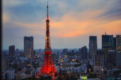 Illuminated buildings in city against sky during sunset