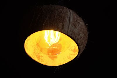 Low angle view of illuminated lamp against black background