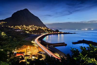 Illuminated cityscape by sea at night