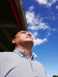 Low angle view of young woman against sky