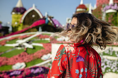 Close-up of young woman tossing hair in ornamental garden 