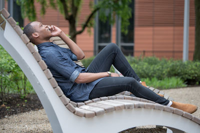 Side view of young man sitting outdoors