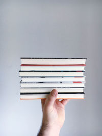 Cropped hand holding books against grey background
