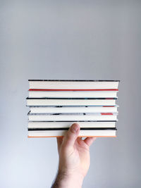 Cropped hand holding books against black background