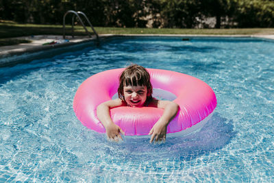 Portrait of smiling girl with inflatable ring in swimming pool