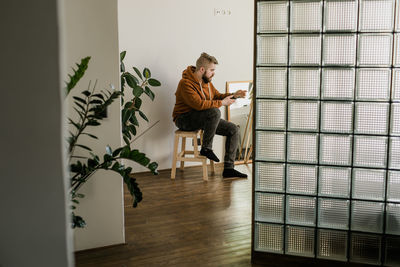 Side view of young woman standing by window