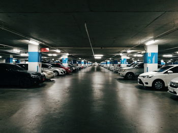 Cars parked in illuminated parking lot at night