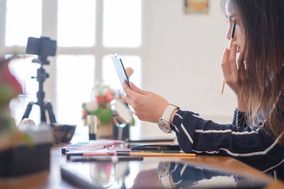 Midsection of woman using smart phone on table