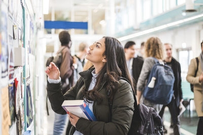 Young woman reading posters in university