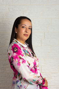 Portrait of smiling woman standing against wall