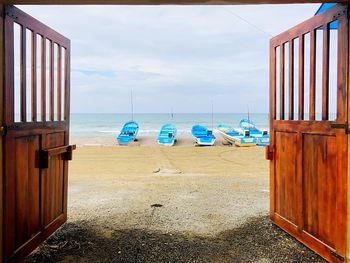 Deck chairs on beach against sky