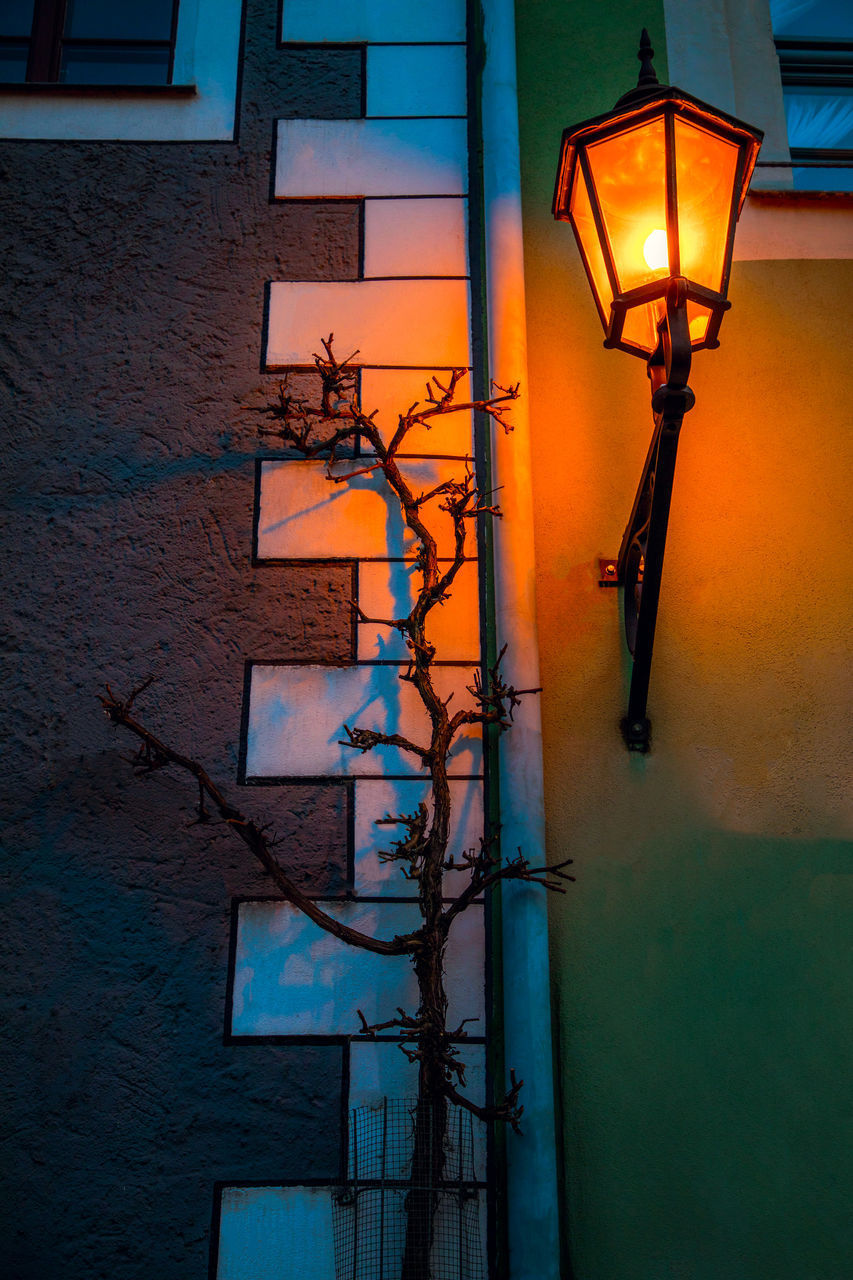 LOW ANGLE VIEW OF ILLUMINATED STREET LIGHT AGAINST WALL