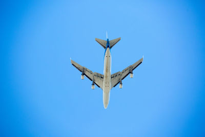 Low angle view of airplane against clear blue sky