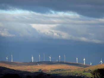 View of wind turbines on landscape against sky