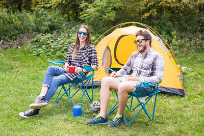 Full length of young couple sitting on plants