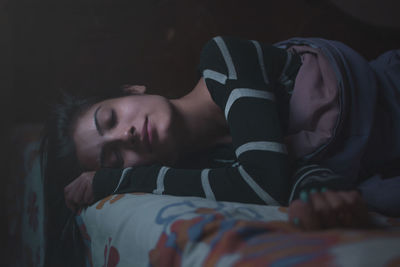 Close-up of young woman sleeping on bed at home