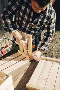 Mid adult male farmer making wooden crate using screwdriver