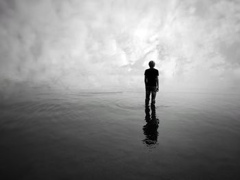 Rear view of silhouette man standing at beach against sky