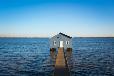 Building by sea against clear blue sky