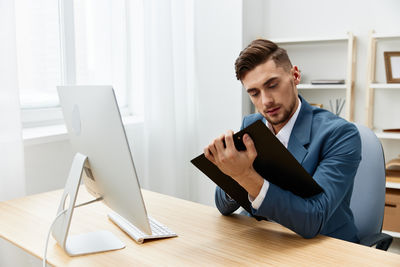 Side view of man using digital tablet while sitting on table