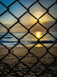 Full frame shot of chainlink fence against sky during sunset