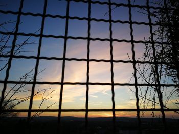 Silhouette fence against sky during sunset