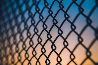Close-up of chainlink fence against gradient sky