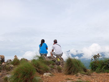 Rear view of men looking at plants against sky