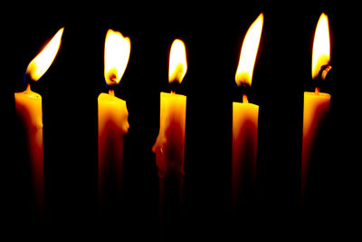 Close-up of burning candles against black background