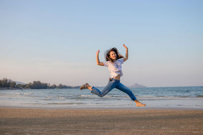 Full length of man jumping on beach against sky