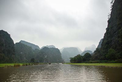 Scenic view of river by mountains against sky