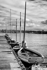 Boats moored at harbor against sky