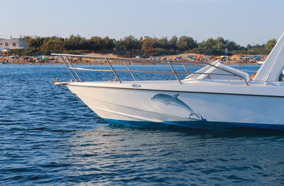 Sailboats moored in sea against clear blue sky