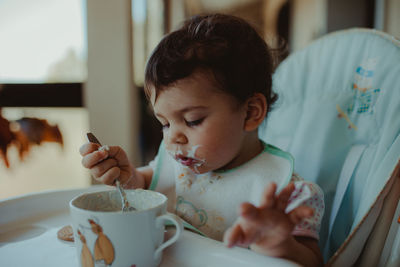 Cute baby girl eating food at home