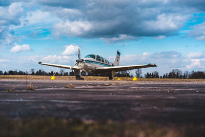 Airplane flying over airport runway against sky