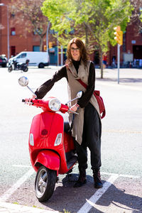 Happy cheerful girl driving scooter through city street.