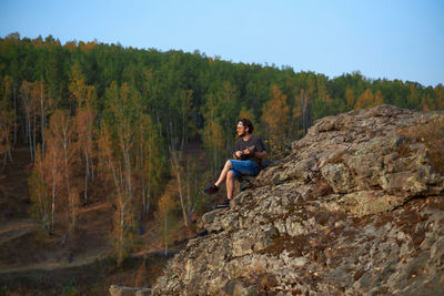Full length of man sitting on rock