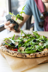 Midsection of man holding pizza on table