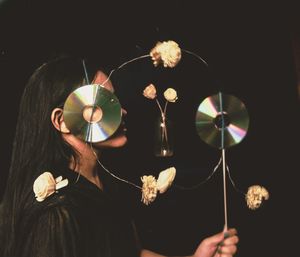 Midsection of woman holding illuminated lighting equipment against black background