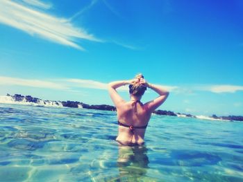 Rear view of woman in sea against blue sky