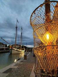 Sailboats moored at harbor against sky during sunset