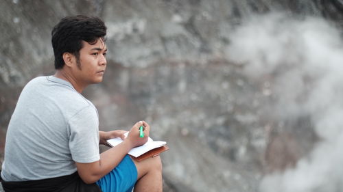 Side view of young man holding rock