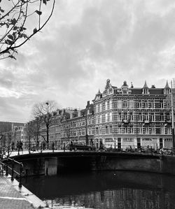 Buildings by river against sky in city