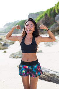 Portrait of smiling young woman standing at beach