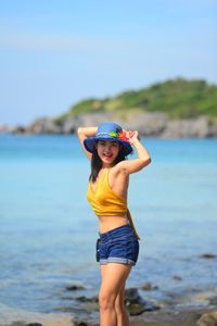 Full length of woman standing at beach against sky