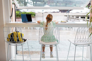 Rear view of girl doing homework at home