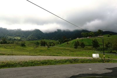 View of country road against cloudy sky