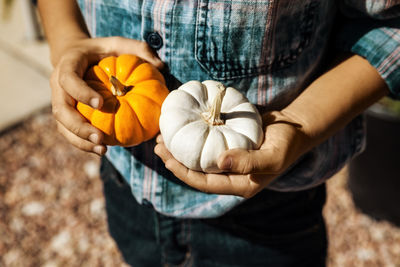 Midsection of man holding pumpkins while standing outdoors