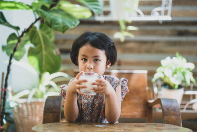 Portrait of boy drinking glass on table at restaurant